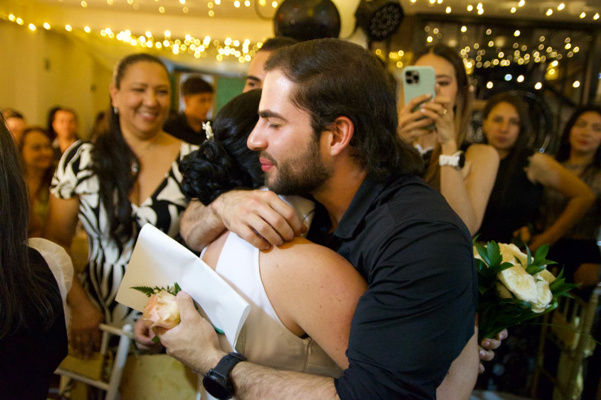 Abrazo entre el novio y una invitada, rodeados por los asistentes a la ceremonia
