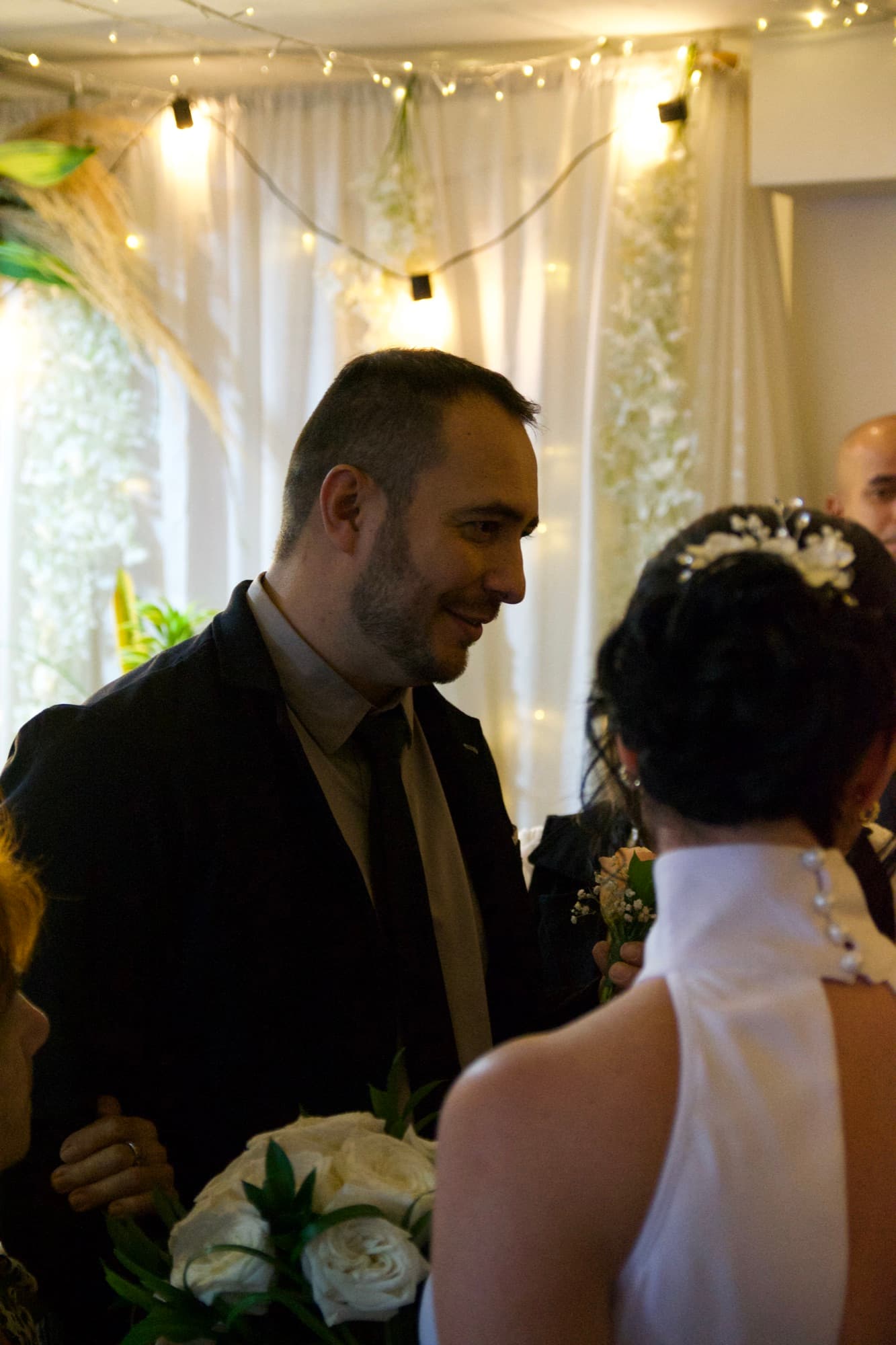El novio sonríe mirando a la novia, de espaldas en primer plano