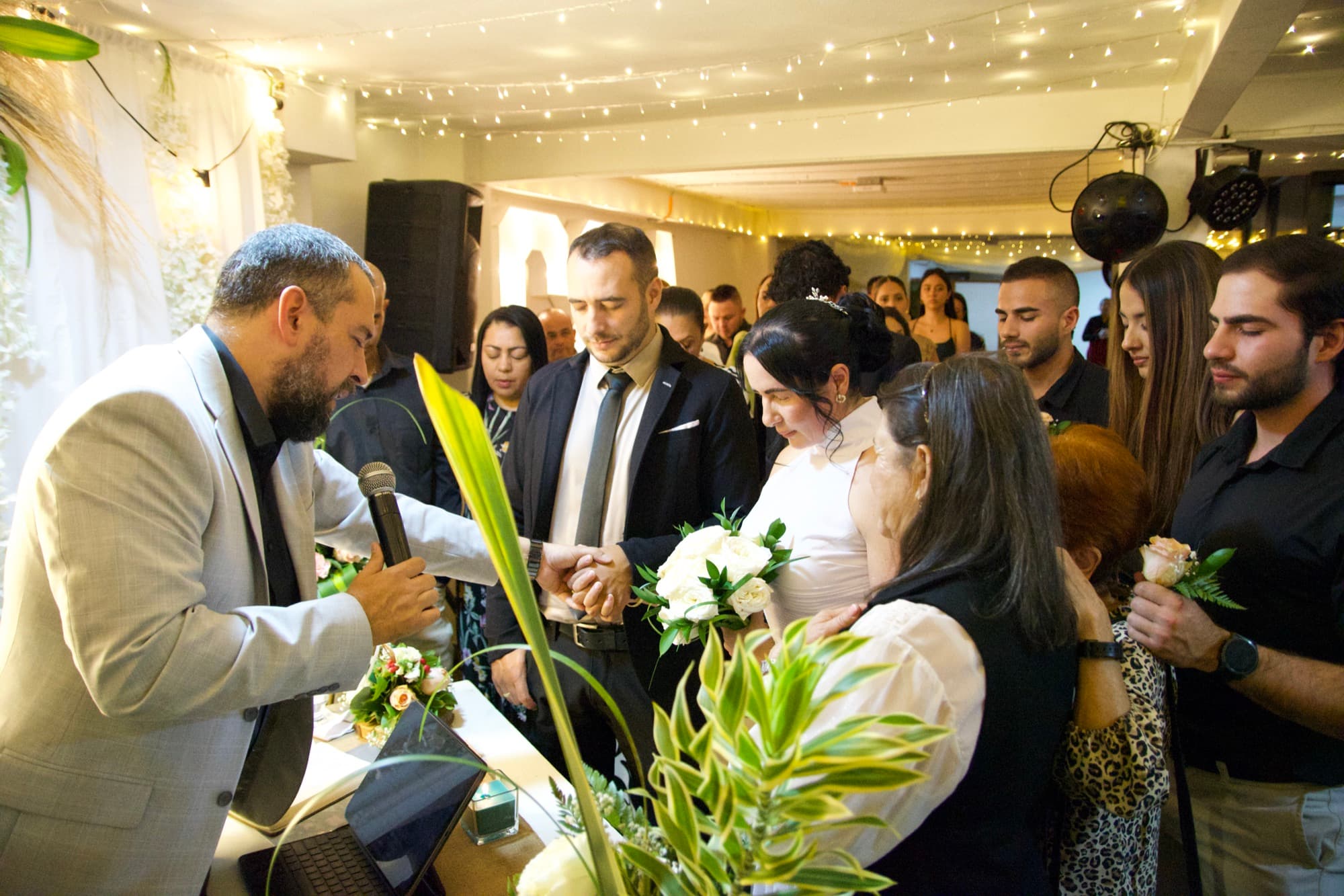 El oficiante dirige la ceremonia mientras los novios se toman de las manos, rodeados de invitados