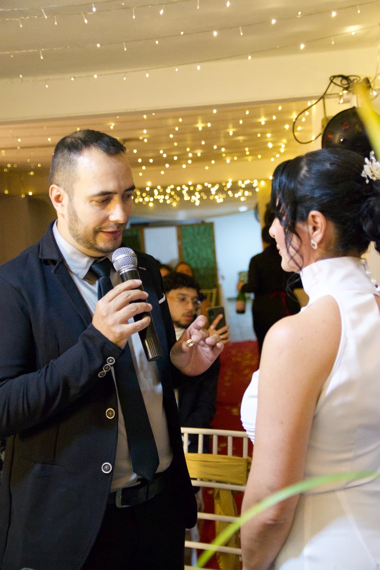 El novio habla por el micrófono mirando a la novia durante los votos