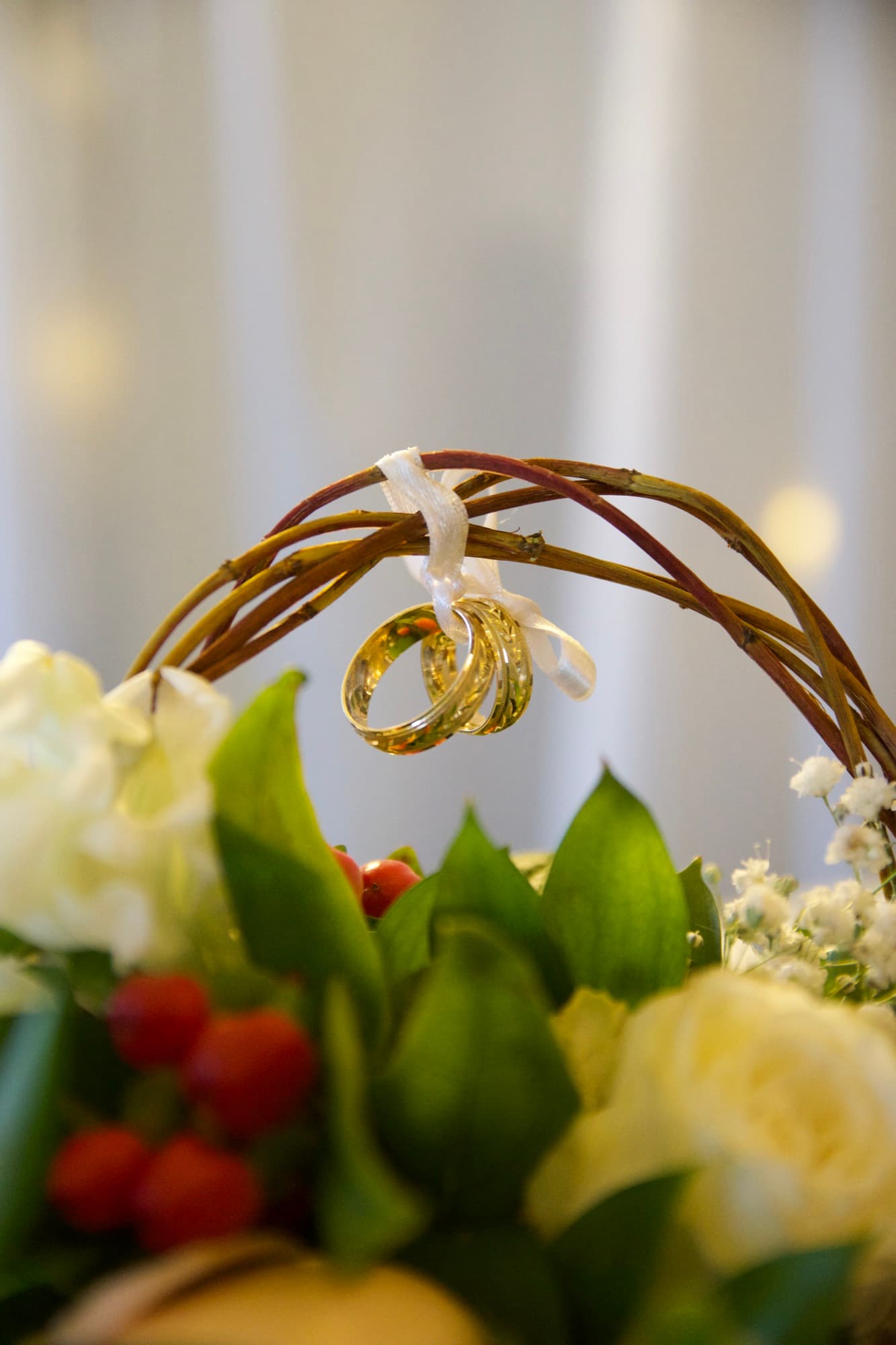 Los anillos colgando con una cinta de una cesta de mimbre adornada con flores
